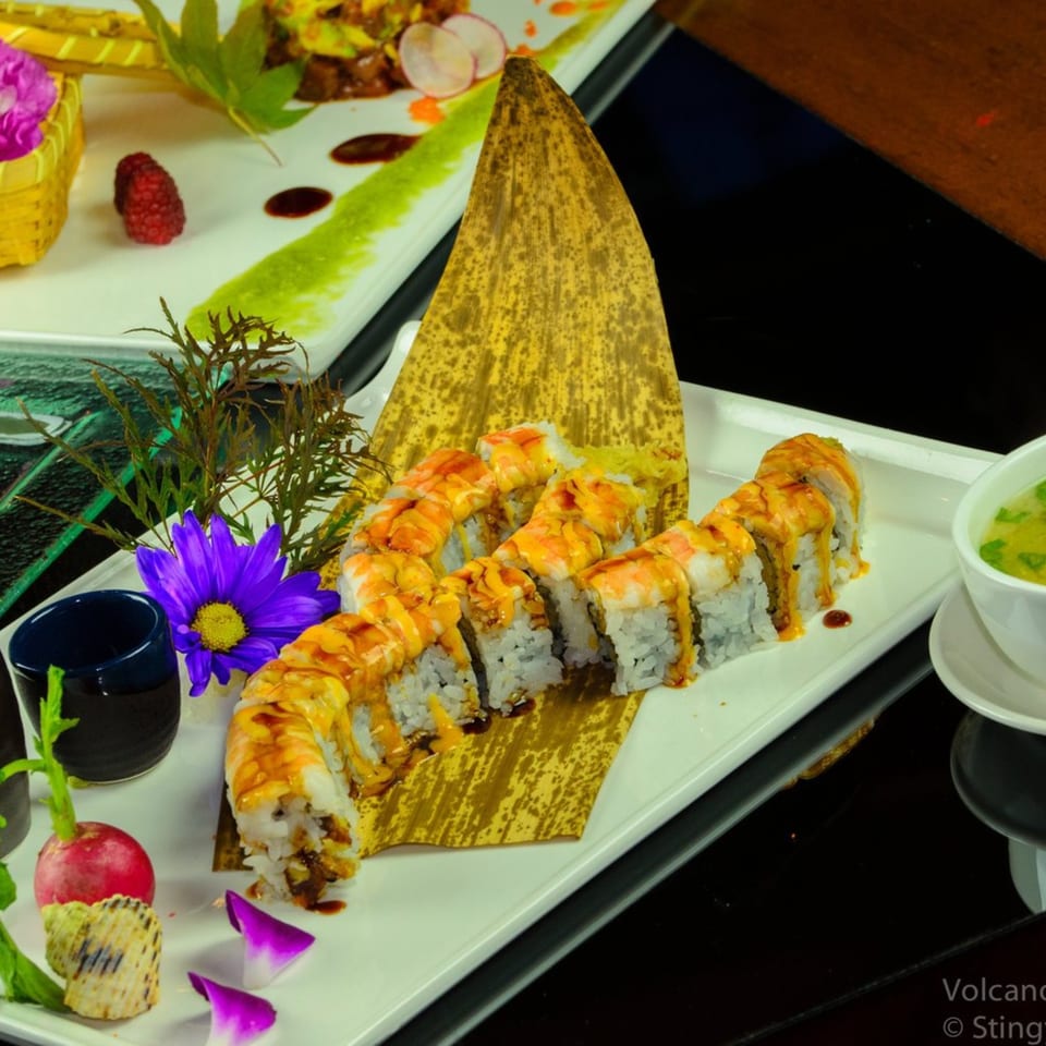 Okinawa Steak & Sushi's Volcano Roll, with shrimp and sauce, garnished with a purple flower.